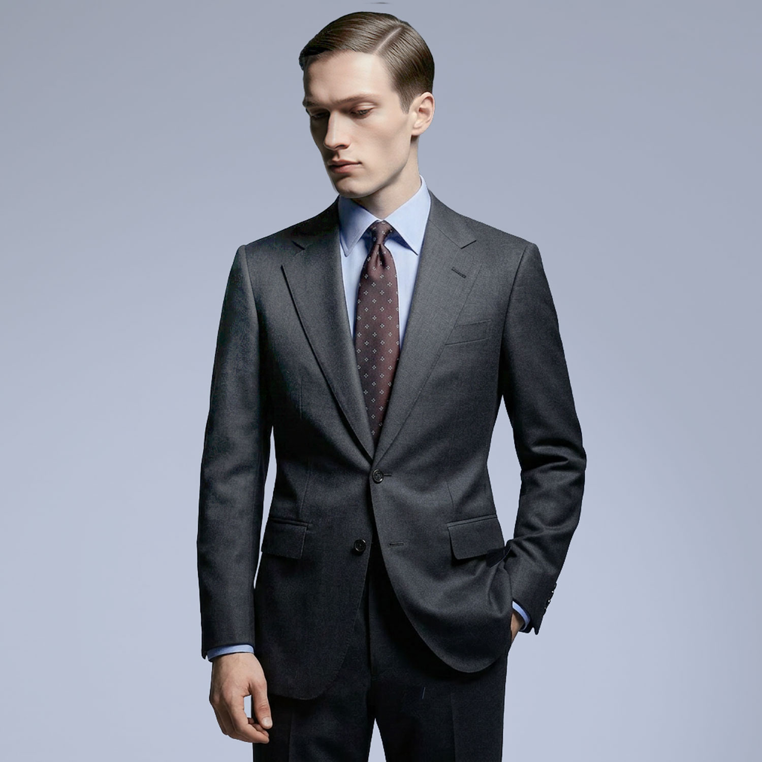 Man in charcoal tailored suit with tie looking down in studio setting