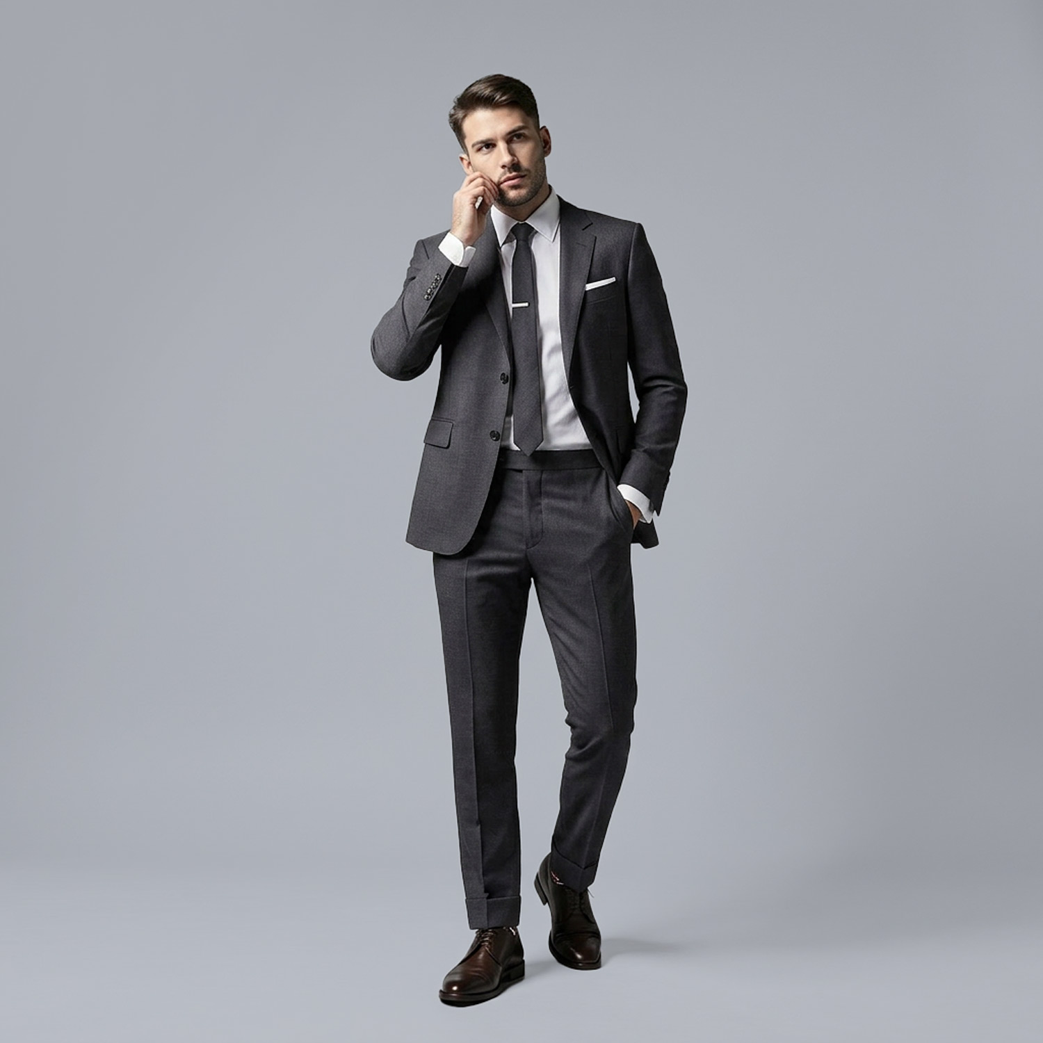 Man in tailored grey suit adjusting cuff while walking against a clean studio background